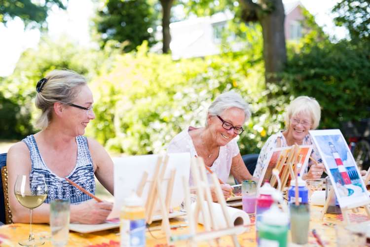 group of woman painting and drinking wine outdoors