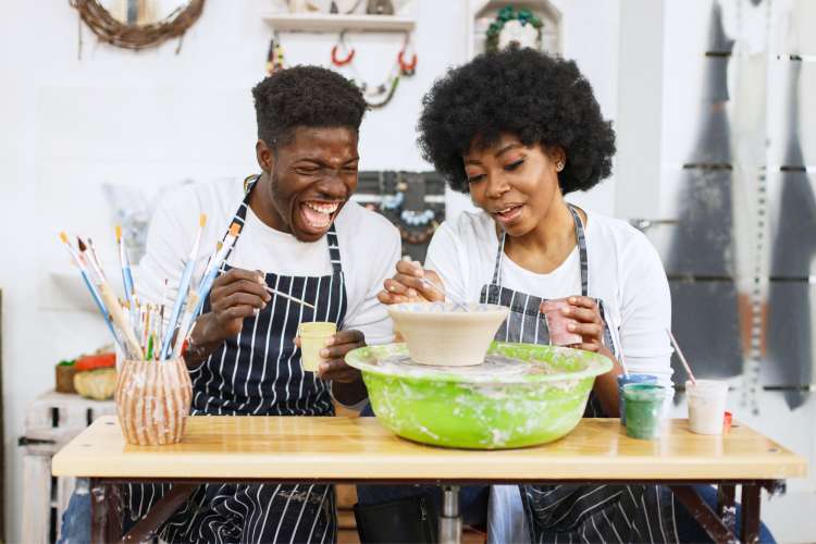 couple laughing while molding clay in pottery classes in Portland