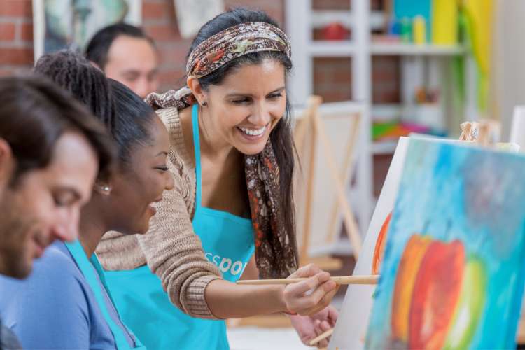 instructor leading student in painting class